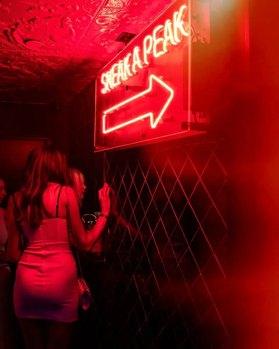 Guest beneath a red neon arrow sign